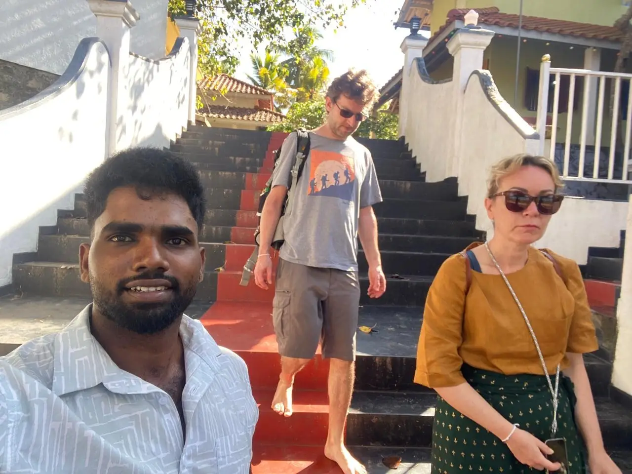 A guide with two guests on the red and white painted steps of a temple